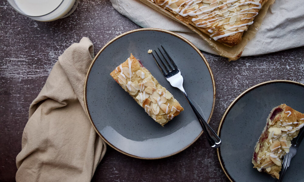 Slice of Bakewell Tart on a plate next to the whole tart