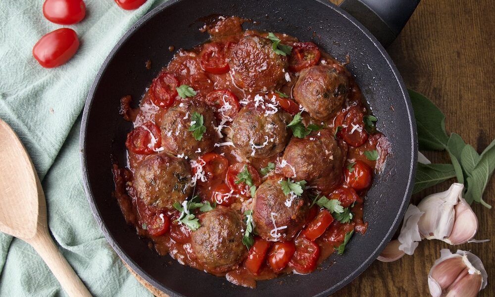 meatballs in tomato sauce with tomatoes and cheese in a pan