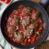 meatballs in tomato sauce with tomatoes and cheese in a pan