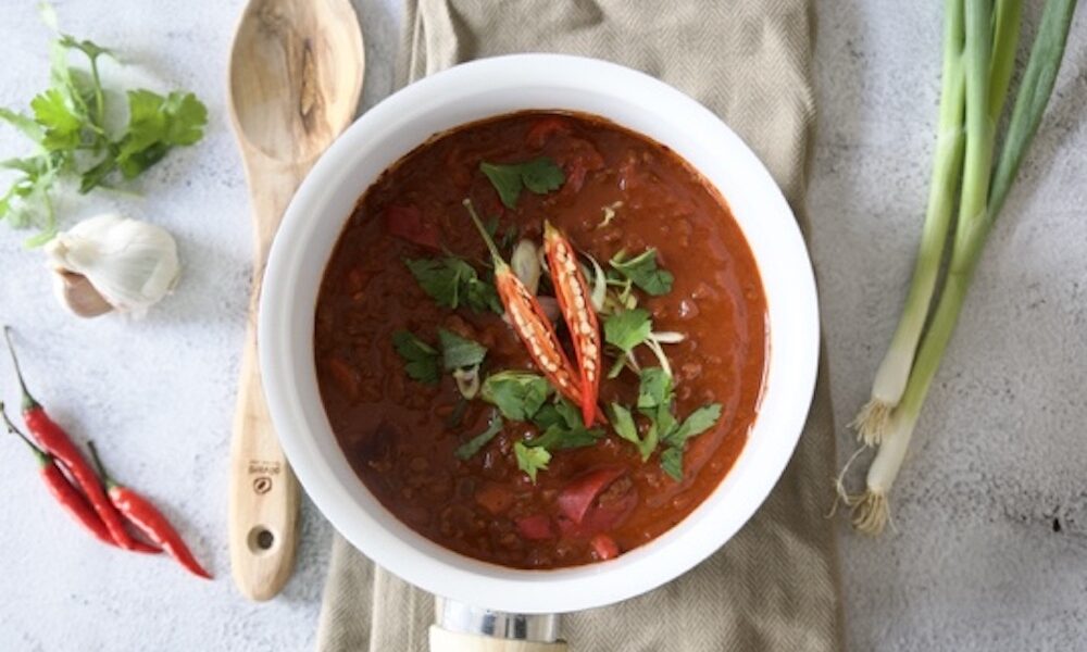 chilli con carne in a saucepan with chilli and coriander garnish