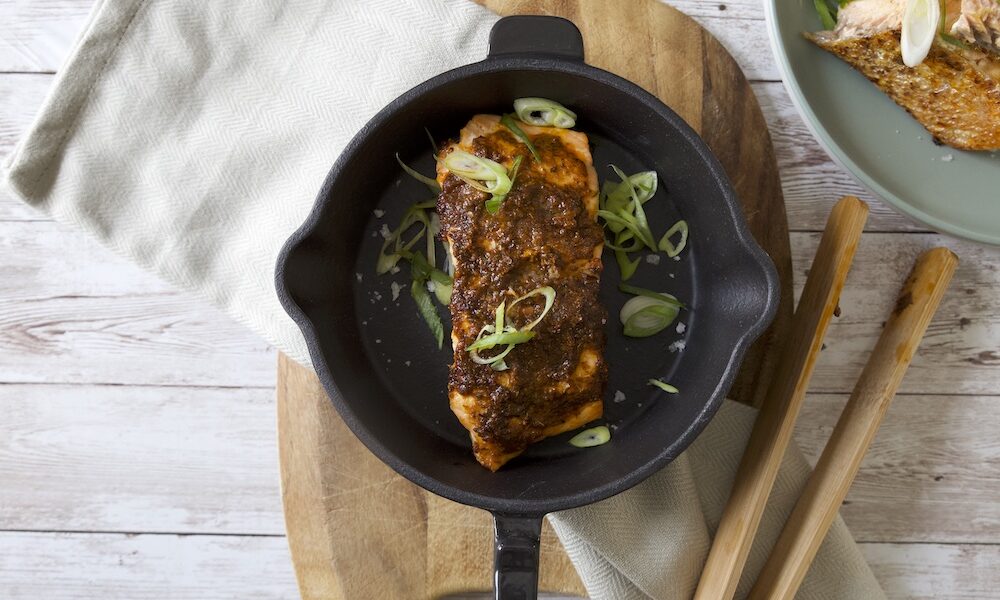 blackened salmon in a skillet with spring onion