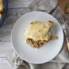 Shepherd's pie on a plate with the pie on the left and cutlery on the right